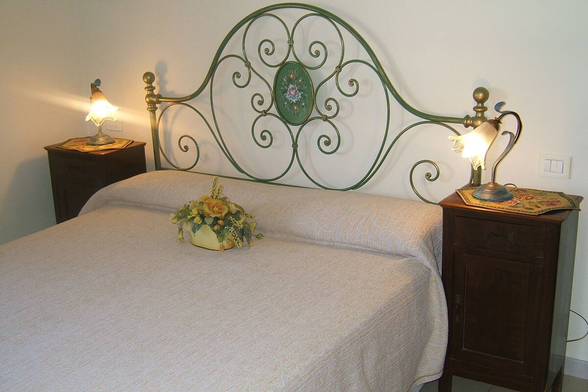 A bed with a floral arrangement, two bedside tables with lamps, and a decorative metal headboard.