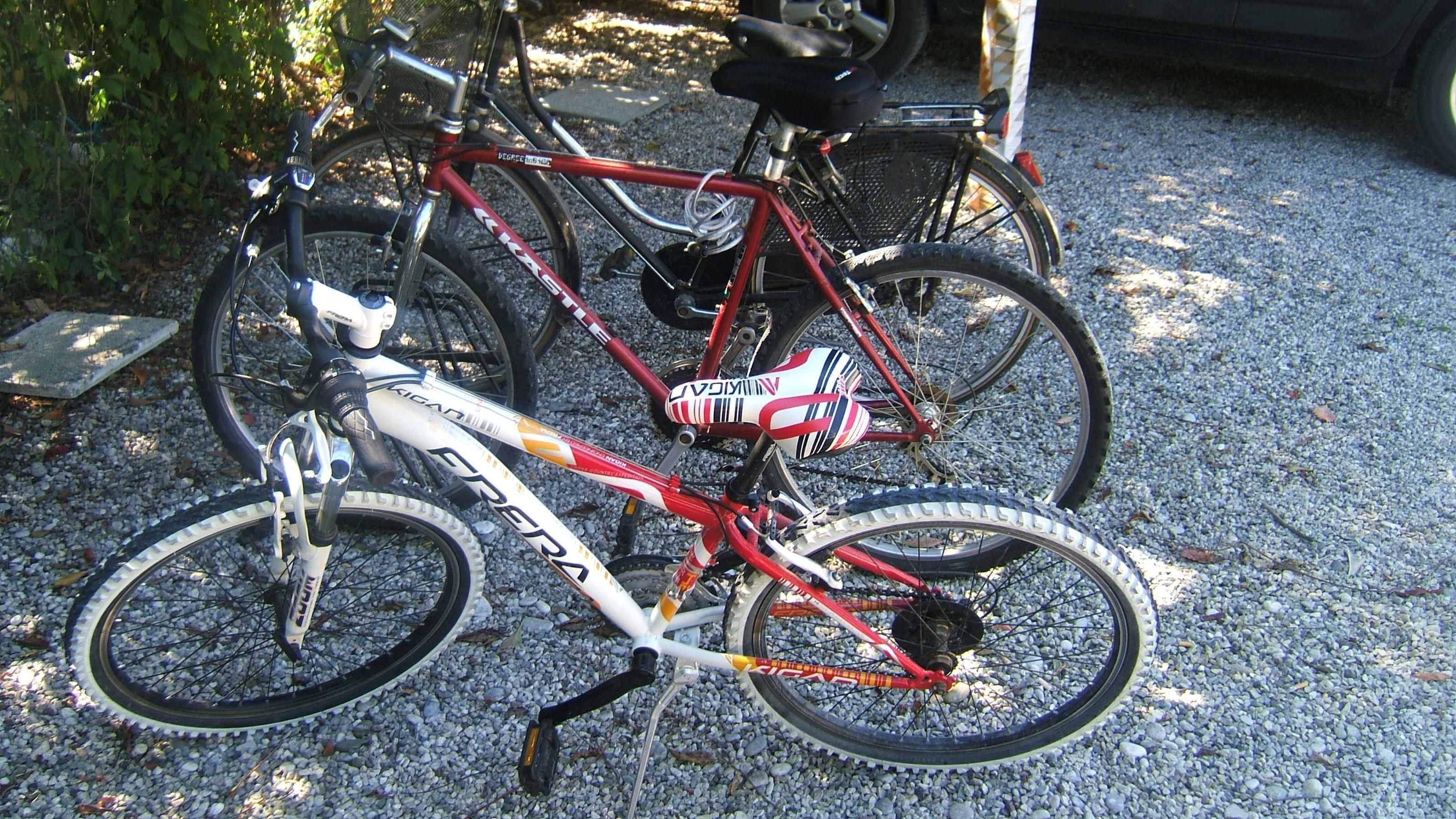 Una bicicletta dal telaio rosso e dettagli bianchi e neri, parcheggiata su ghiaia.