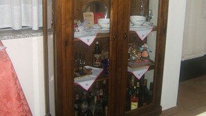 A wooden cabinet with glass doors, containing various kitchenware and bottles. - Locanda Canareggio (San Biagio di Callalta)