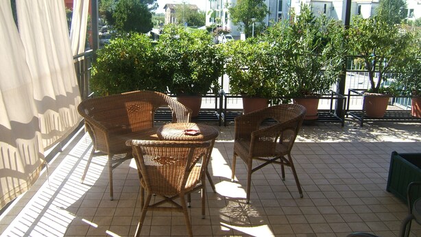 A terrace with wicker furniture and potted plants. - Locanda Canareggio (San Biagio di Callalta)