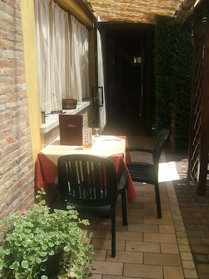 A small outdoor dining area with a table and chairs, a potted plant, and a brick wall. - Locanda Canareggio (San Biagio di Callalta)