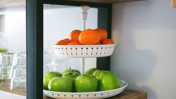 Un puesto de frutas de dos niveles con naranjas y manzanas verdes.