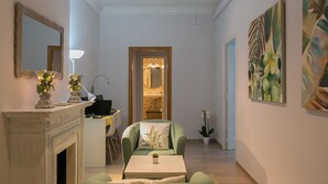 A modern living room with a fireplace, a dining area, and a hallway leading to a bathroom. - Blanc Guesthouse (Barcelona)