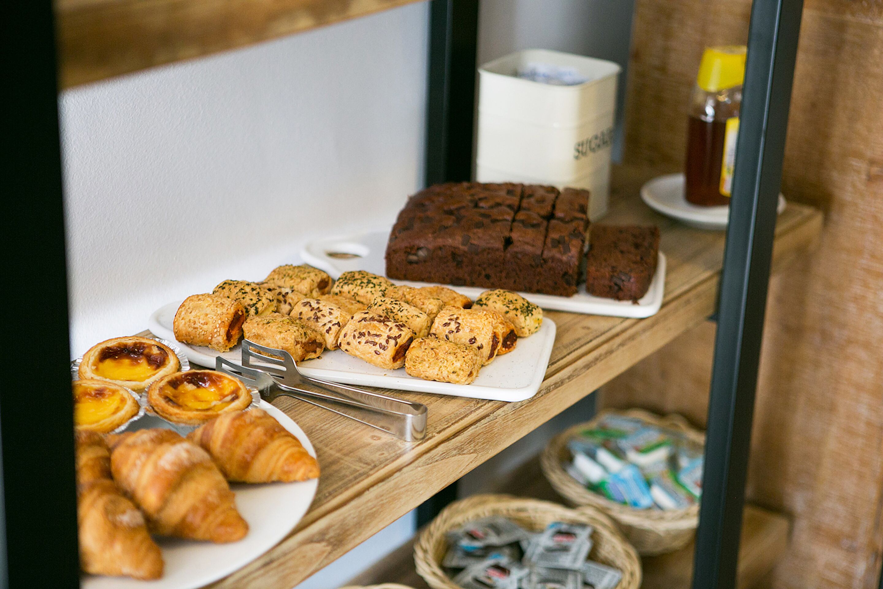 En frukostbuffé med bakverk, bröd och tillbehör.