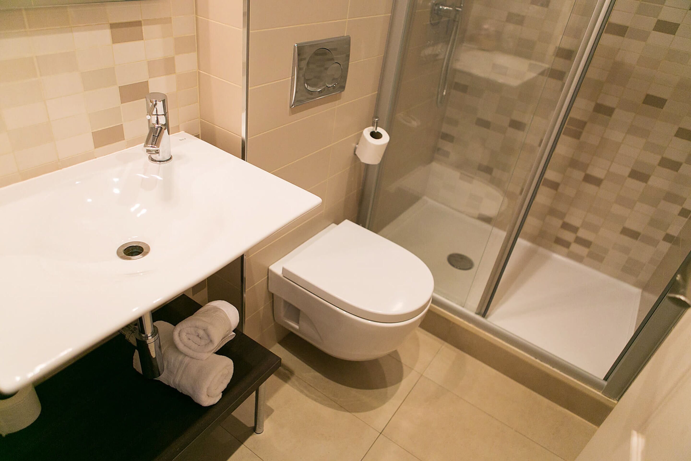 Un baño moderno con un lavamanos blanco, un inodoro y un box de ducha de vidrio.