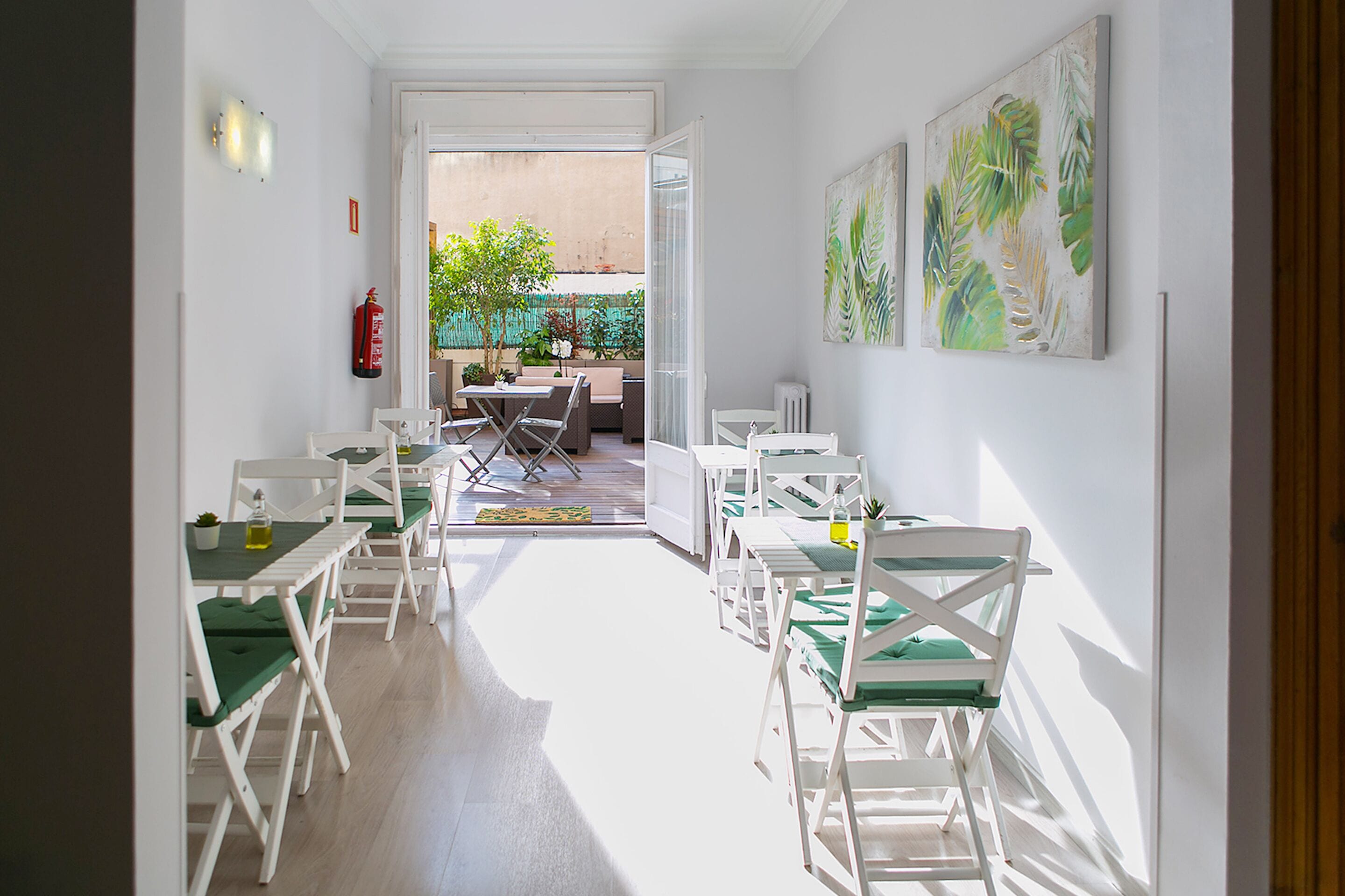 A bright dining area with white furniture and a view of the outdoor patio.