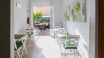 A bright dining area with white furniture and a view of the outdoor patio.