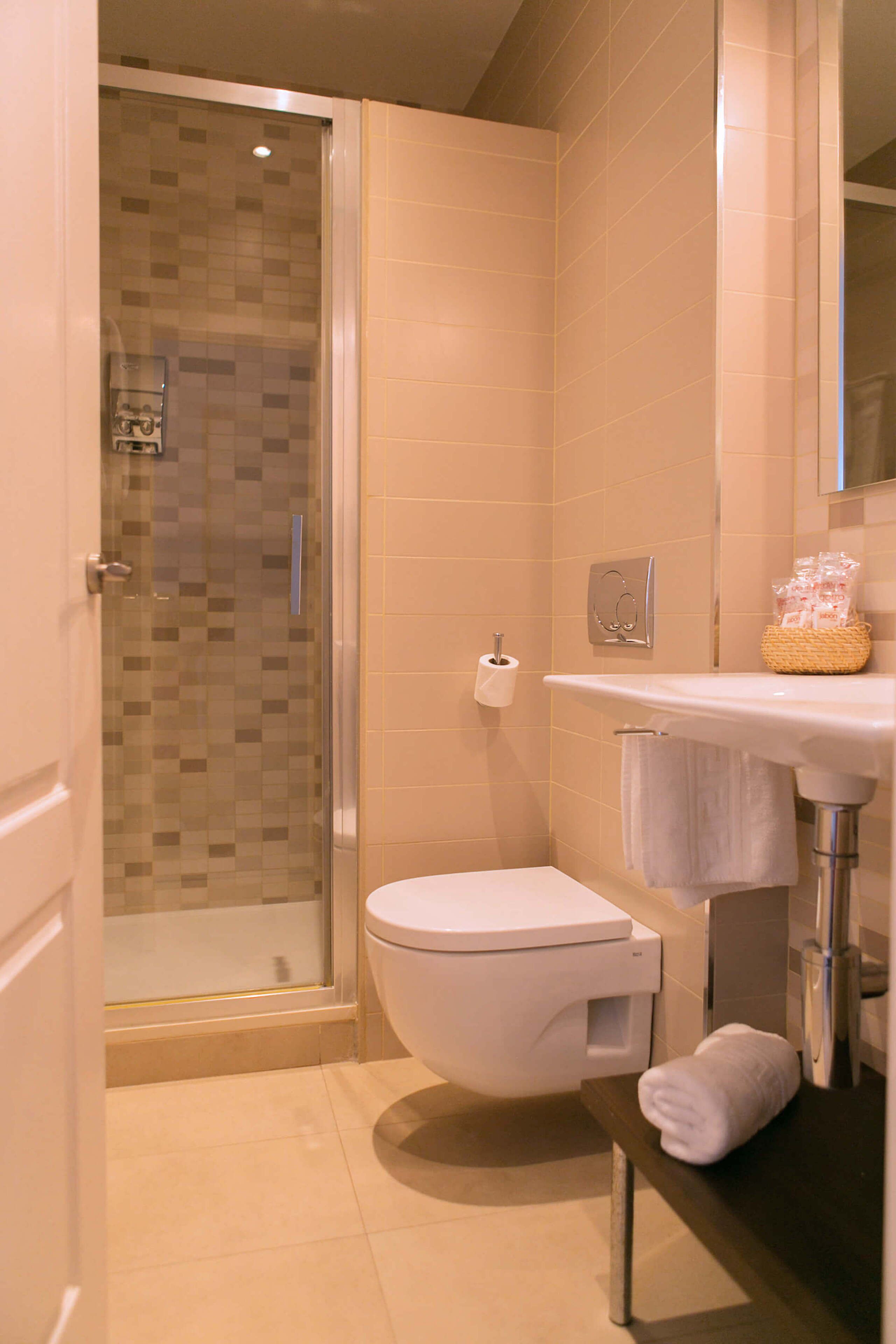 A modern bathroom with a glass-enclosed shower, a toilet, a sink, and a towel rack.