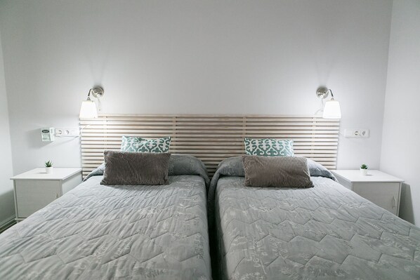 A twin room with two beds, each with a headboard and bedside lamps. - Blanc Guesthouse (Barcelona)