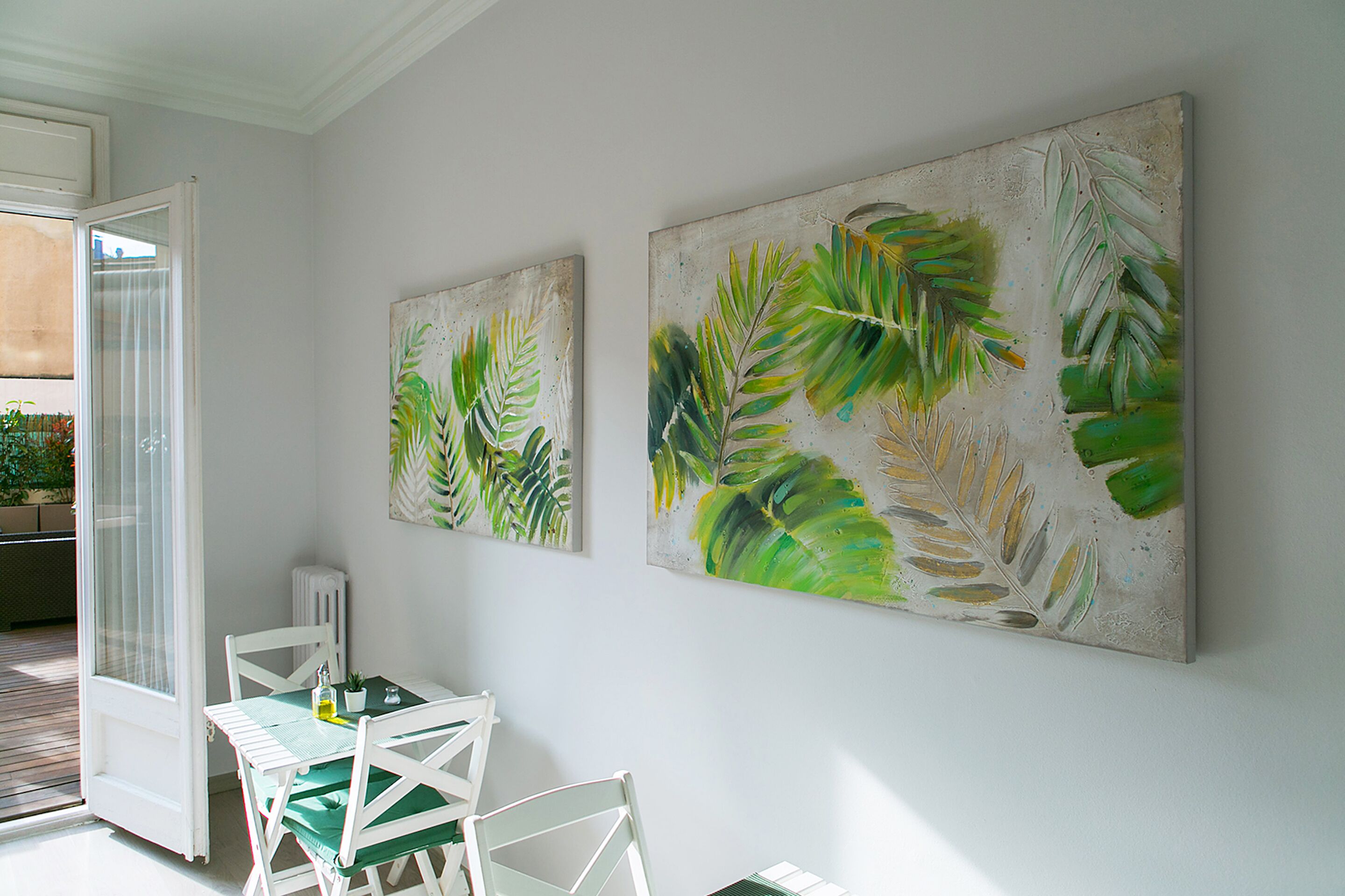 Une pièce comprenant une table à manger et des chaises, un radiateur et deux grandes peintures au mur.