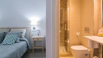 Un dormitorio con cama, mesita de noche y velador.