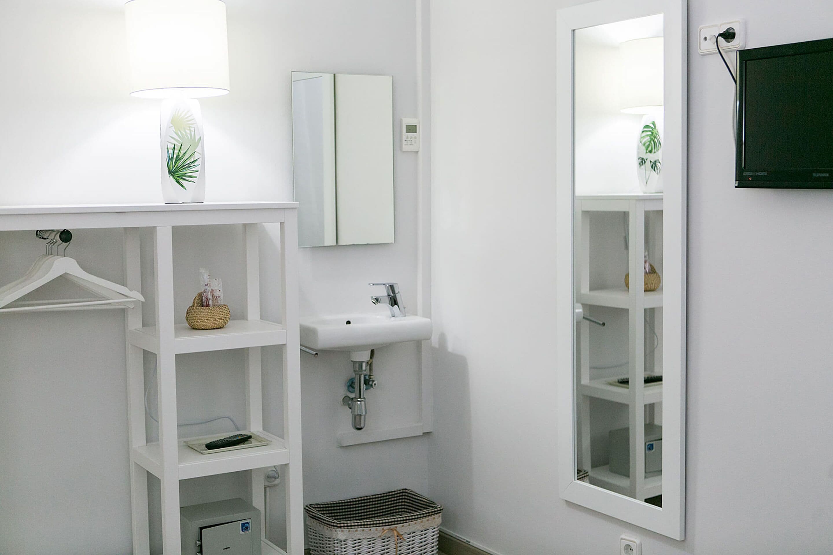 A modern bathroom with a white sink, mirror, and shelves.