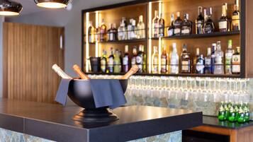 Eine Bar mit einer schwarzen Arbeitsplatte, einer Schüssel mit Brotstangen und Regalen voller Spirituosenflaschen.