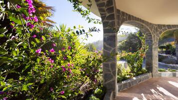Un arco de piedra que da paso a un patio con abundante follaje y plantas en flor.