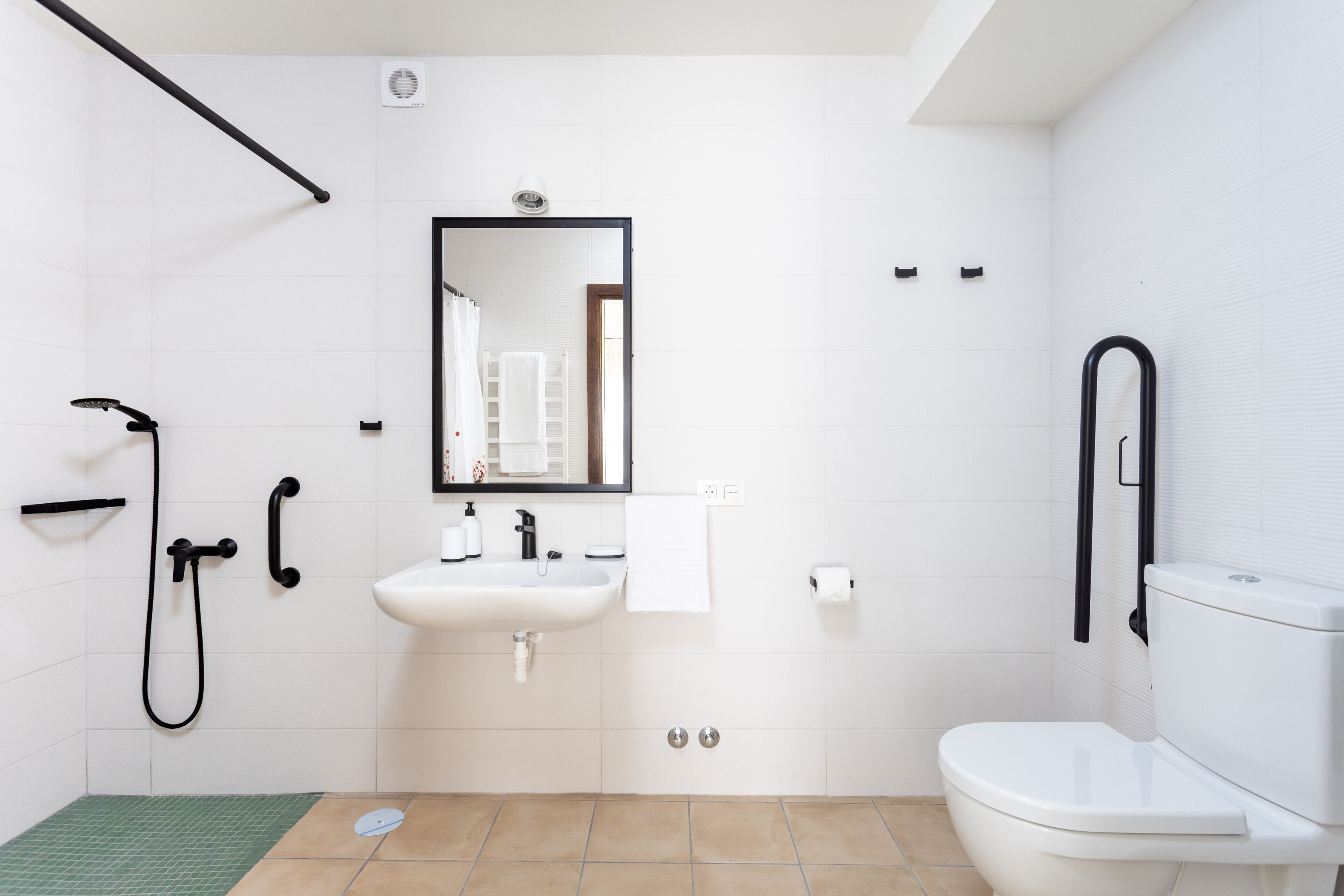 Ein modernes Badezimmer mit Waschbecken, Spiegel und Toilette in Weiß.