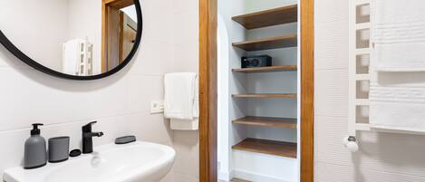 A bathroom with a white sink, black soap dispenser, and a mirror with a black frame.