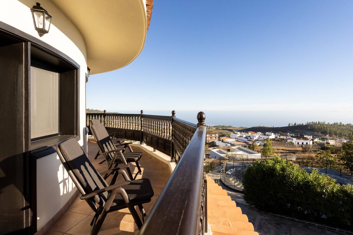 A balcony with chairs and a view of a town.