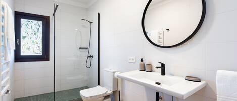 Ein modernes Badezimmer mit Toilette, Waschbecken und Dusche.
