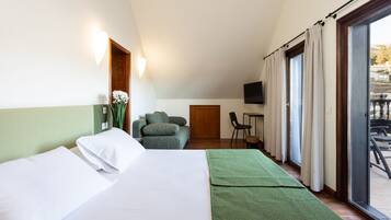 A hotel room with a bed, a green sofa, a small table, and a TV.