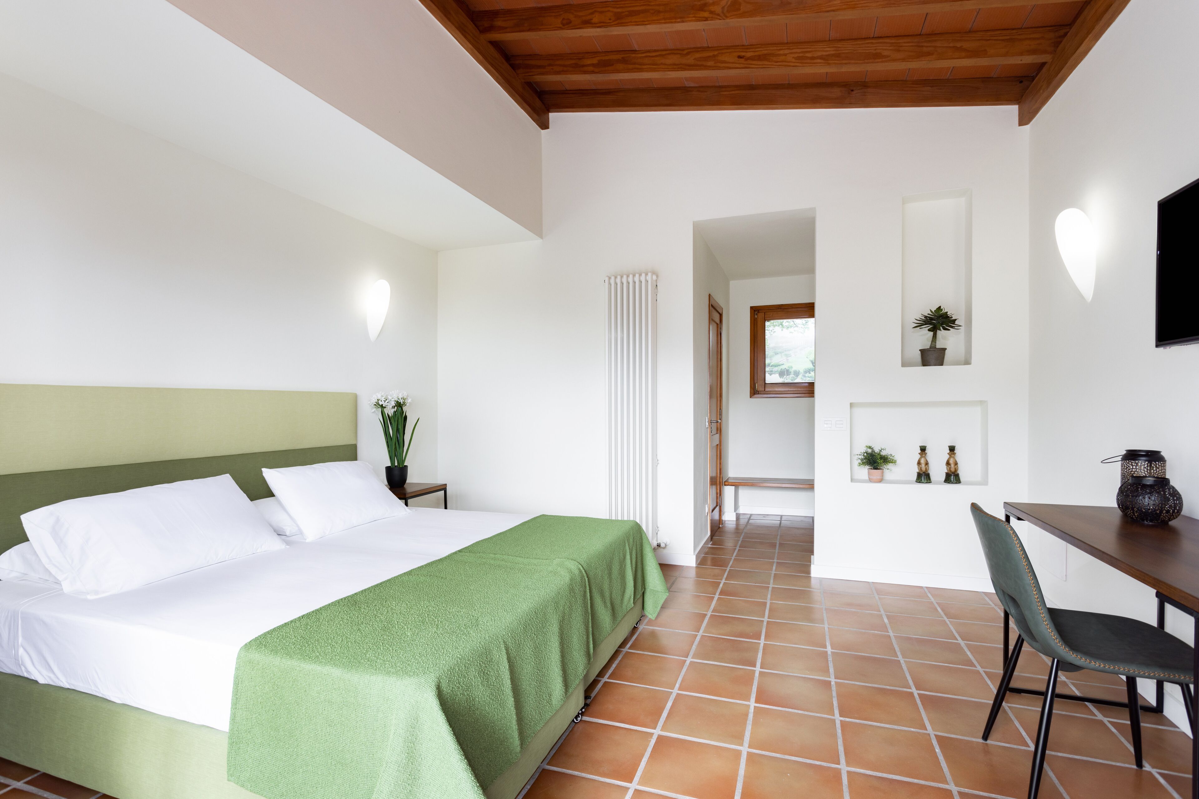 A bedroom with a bed, a desk, and a chair.