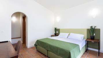 Une chambre à coucher avec un lit, une chaise, une table de chevet et une plante en pot.