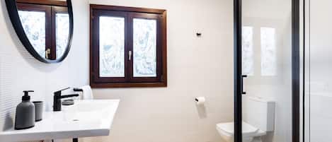 A bathroom with a white sink, a mirror, a window, and a toilet.