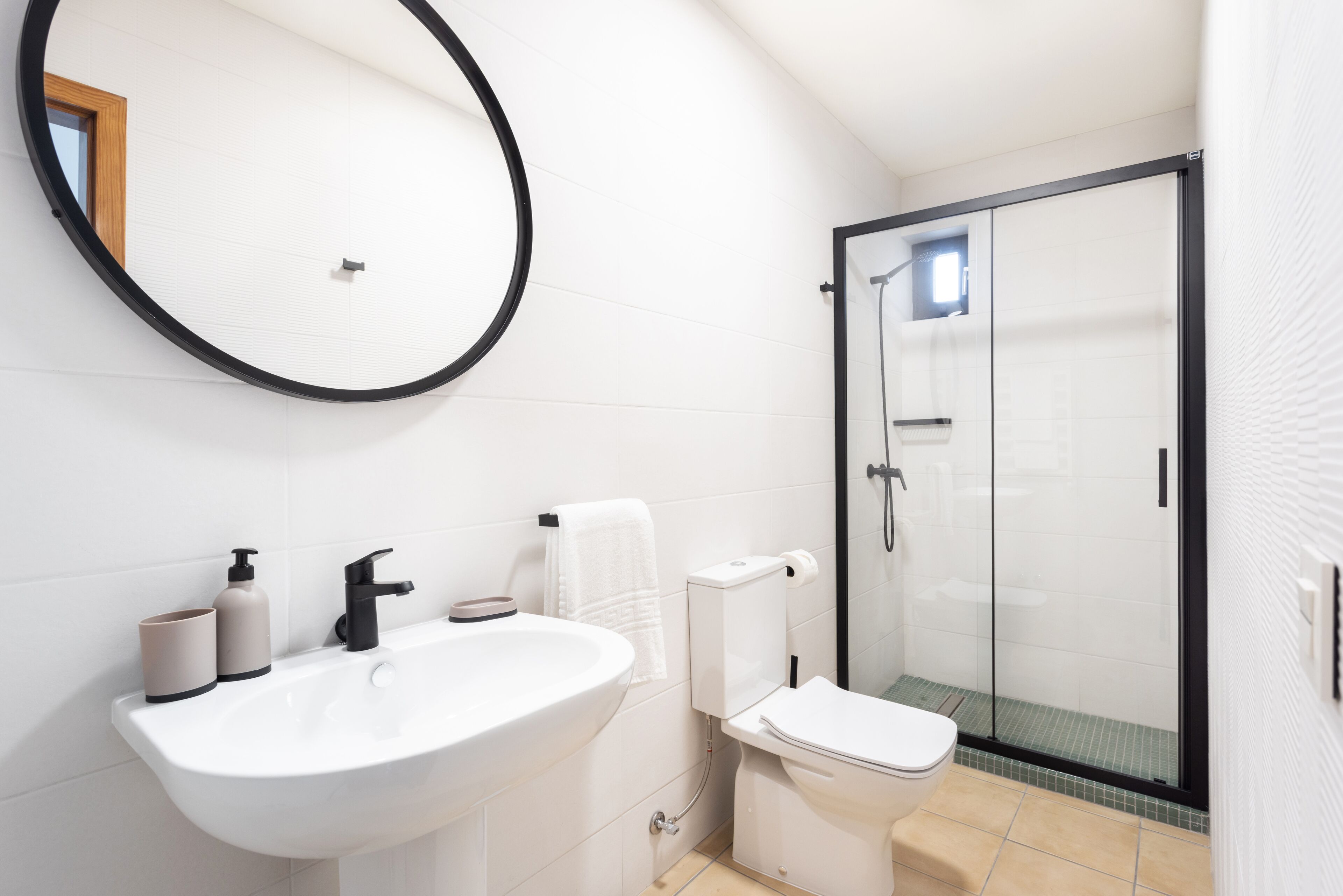 Un baño con lavamanos blanco, inodoro y cabina de ducha.