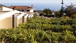 A coastal building with a tiled roof, surrounded by lush greenery and a clear view of the sea. - Hotel Alta Montaña (Vilaflor)