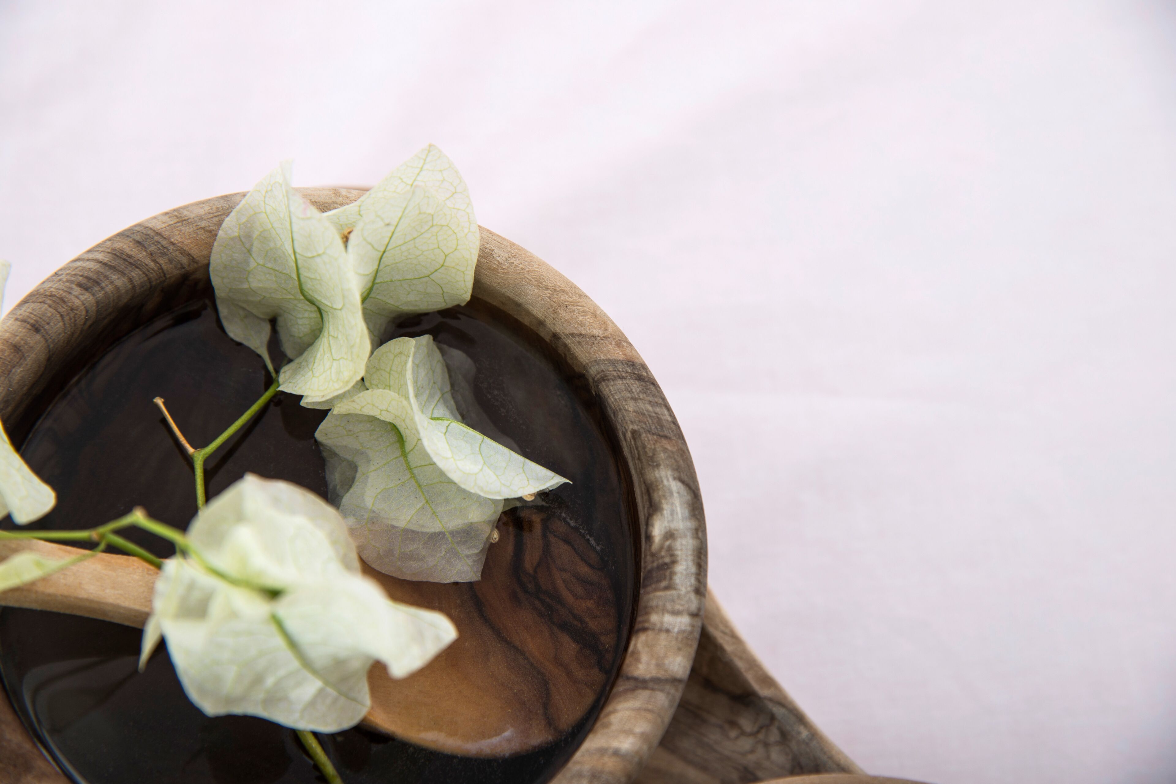 A wooden bowl with water and green leaves.