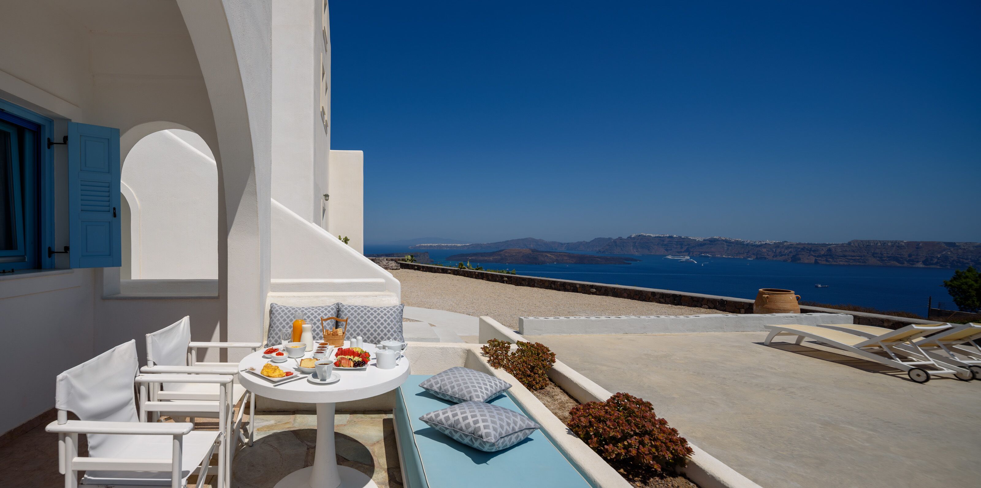 Une terrasse avec une table préparée pour le petit-déjeuner, offrant une vue panoramique sur la côte.