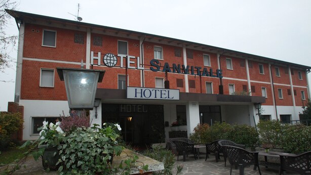 A hotel with a red brick facade, outdoor seating area, and a sign that reads "HOTEL SANVITALA". - Hotel San Vitale (Medicina)