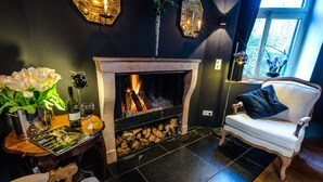 Una habitación acogedora con chimenea, una mesa con un florero y un sillón cómodo.