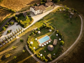 An aerial view of a property with a swimming pool, outdoor seating, and a large building.