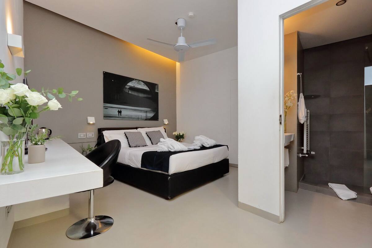 A modern bedroom with a bed, bedside table, and a ceiling fan.