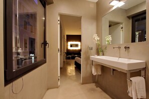 Une salle de bain moderne avec un grand miroir, un lavabo blanc et un porte-serviettes.