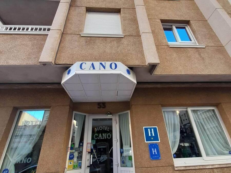 Entrada de un hotel con un cartel que dice "MOTEL CANO" y un letrero azul de accesibilidad para personas con discapacidad.