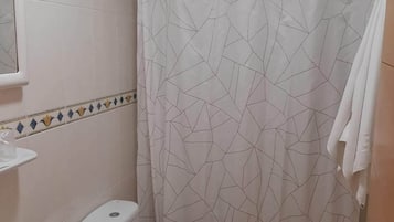 Une salle de bain avec des toilettes, un lavabo et un rideau de douche.