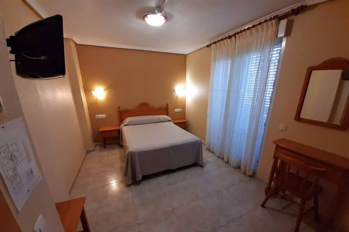 Una habitación de hotel con cama, mesitas de noche, escritorio y silla.