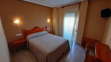Un dormitorio con cama, mesitas de noche, escritorio y silla.