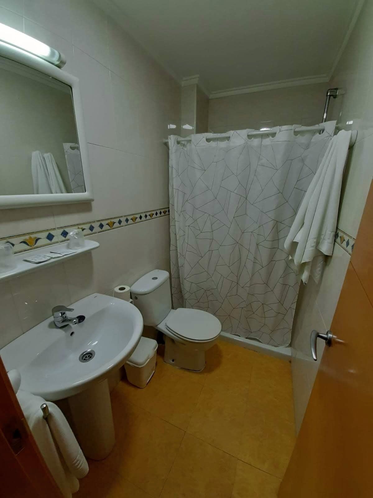 A small bathroom with a sink, toilet, and shower curtain.