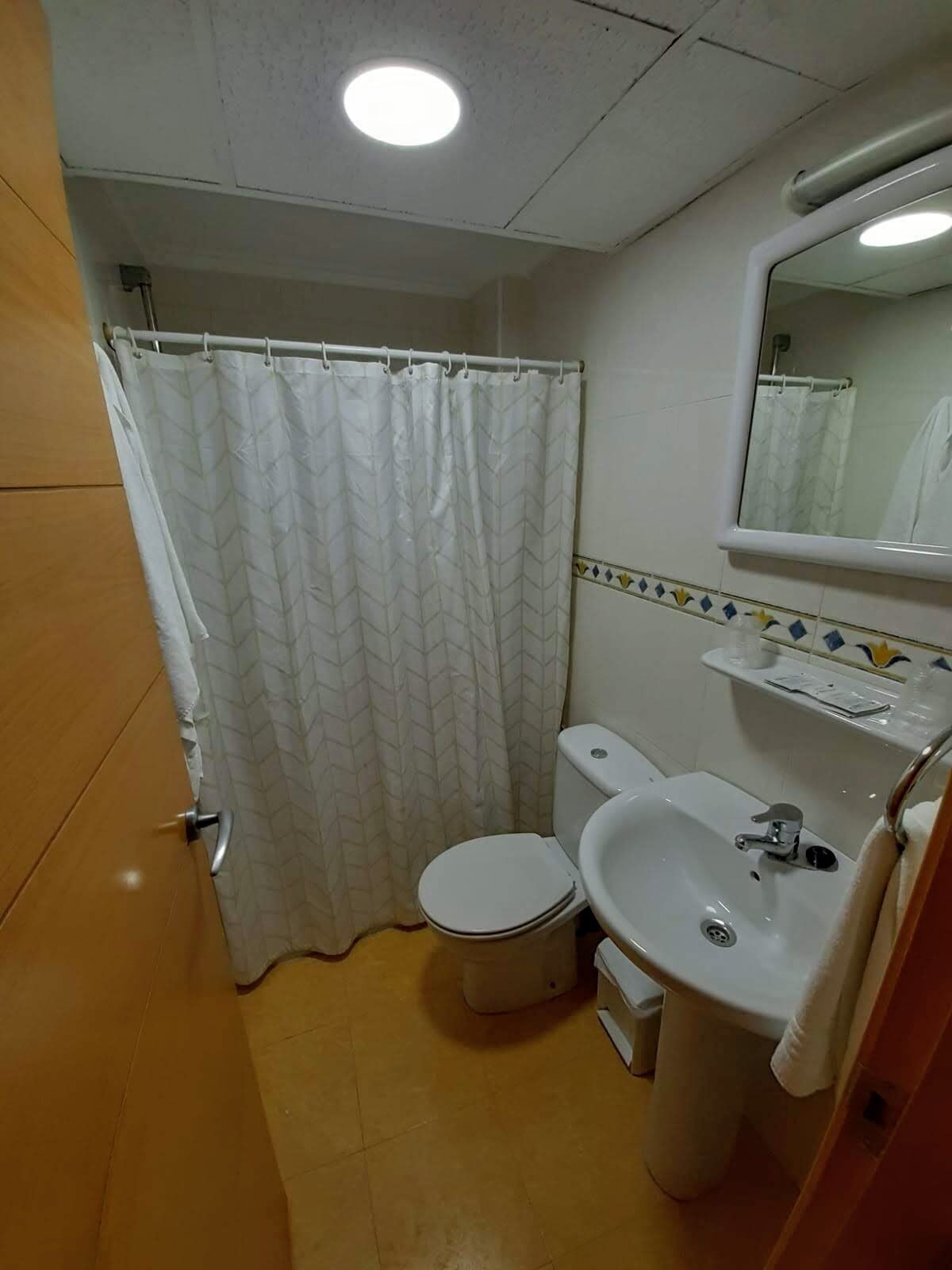 A small bathroom with a toilet, sink, and shower curtain.