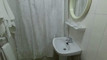 Un baño pequeño con un lavamanos blanco, inodoro y baldosas de suelo verdes.