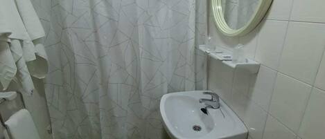 A small bathroom with a white sink, toilet, and green floor tiles.