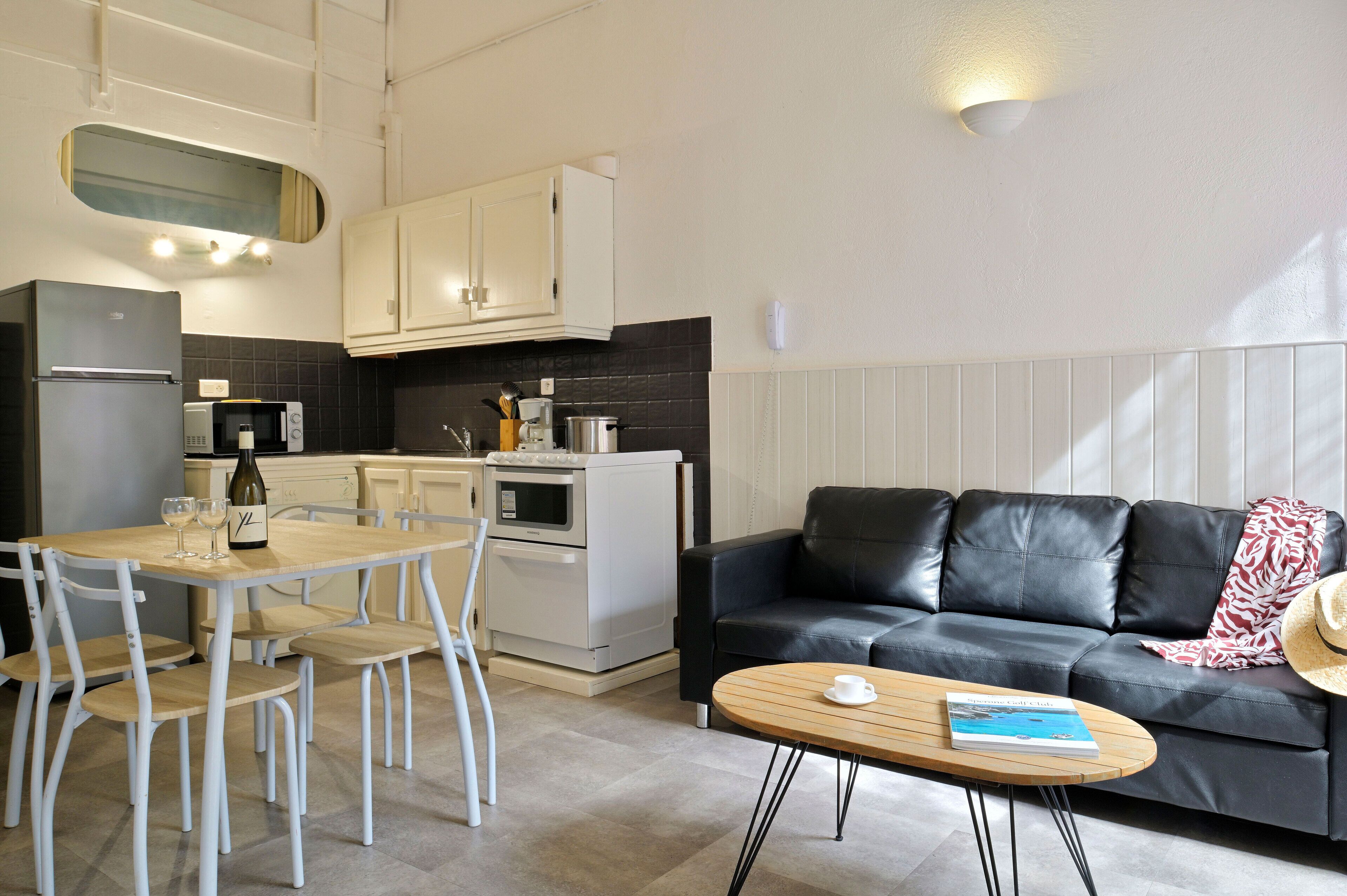 A compact living space with a dining area, a sofa, and a kitchen.