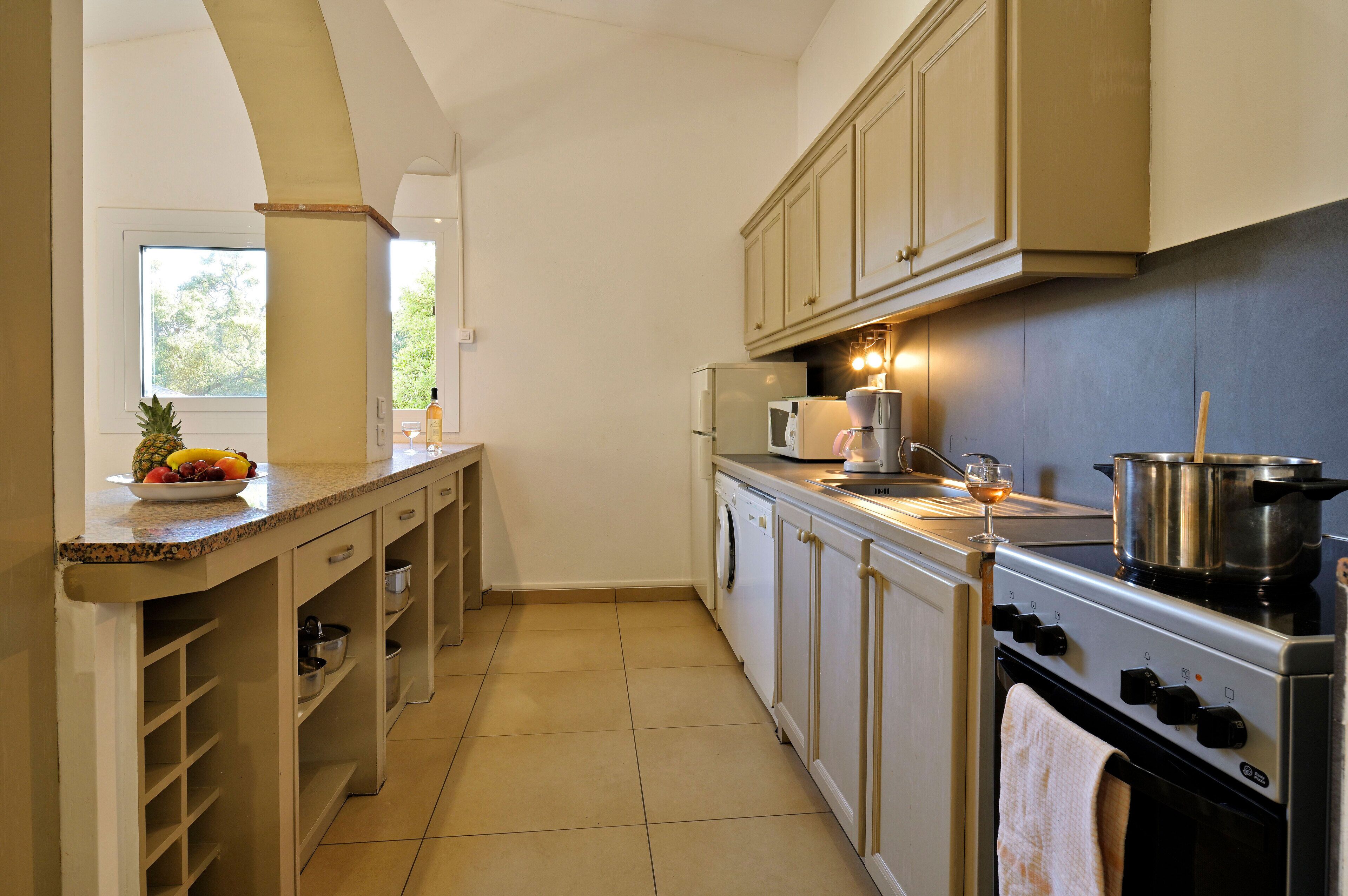 A kitchen with a stove, microwave, and a bowl of fruit on the counter.
