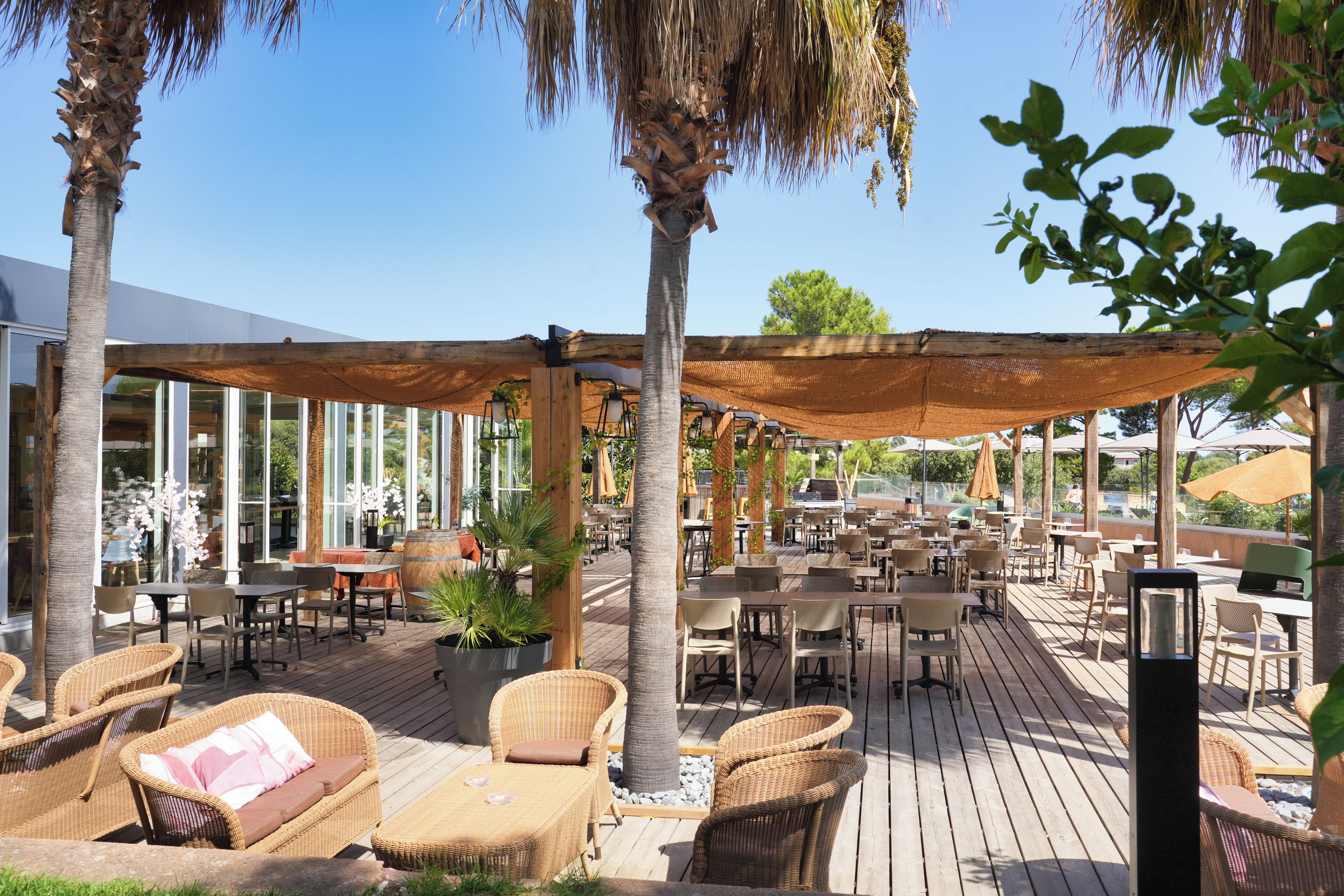 An outdoor patio area with wicker furniture, a wooden deck, and a pergola providing shade.