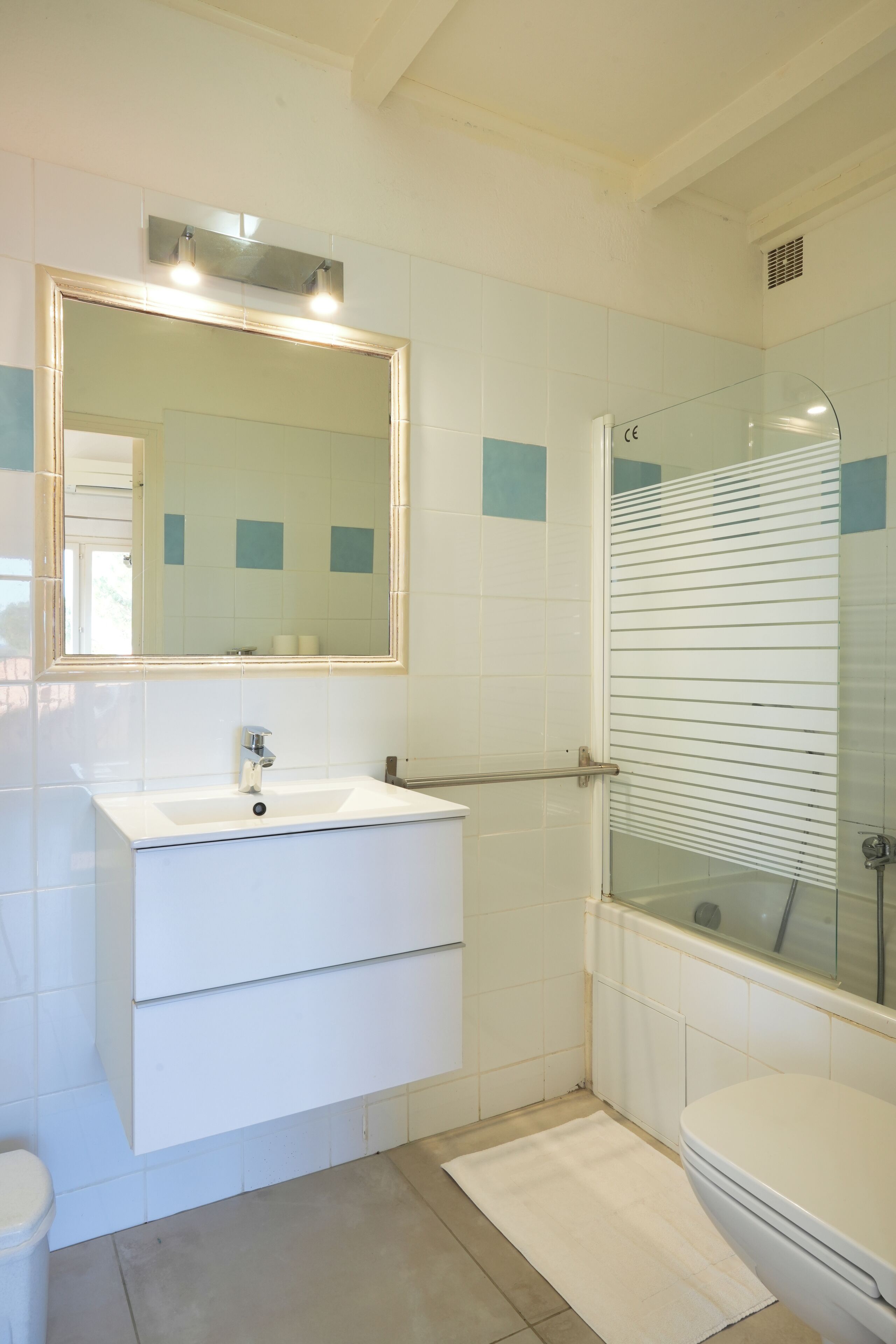 A bathroom with a white sink, mirror, and toilet. There is a glass shower enclosure with a glass door.
