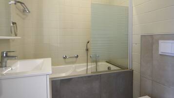 A modern bathroom with a bathtub, toilet, and sink.