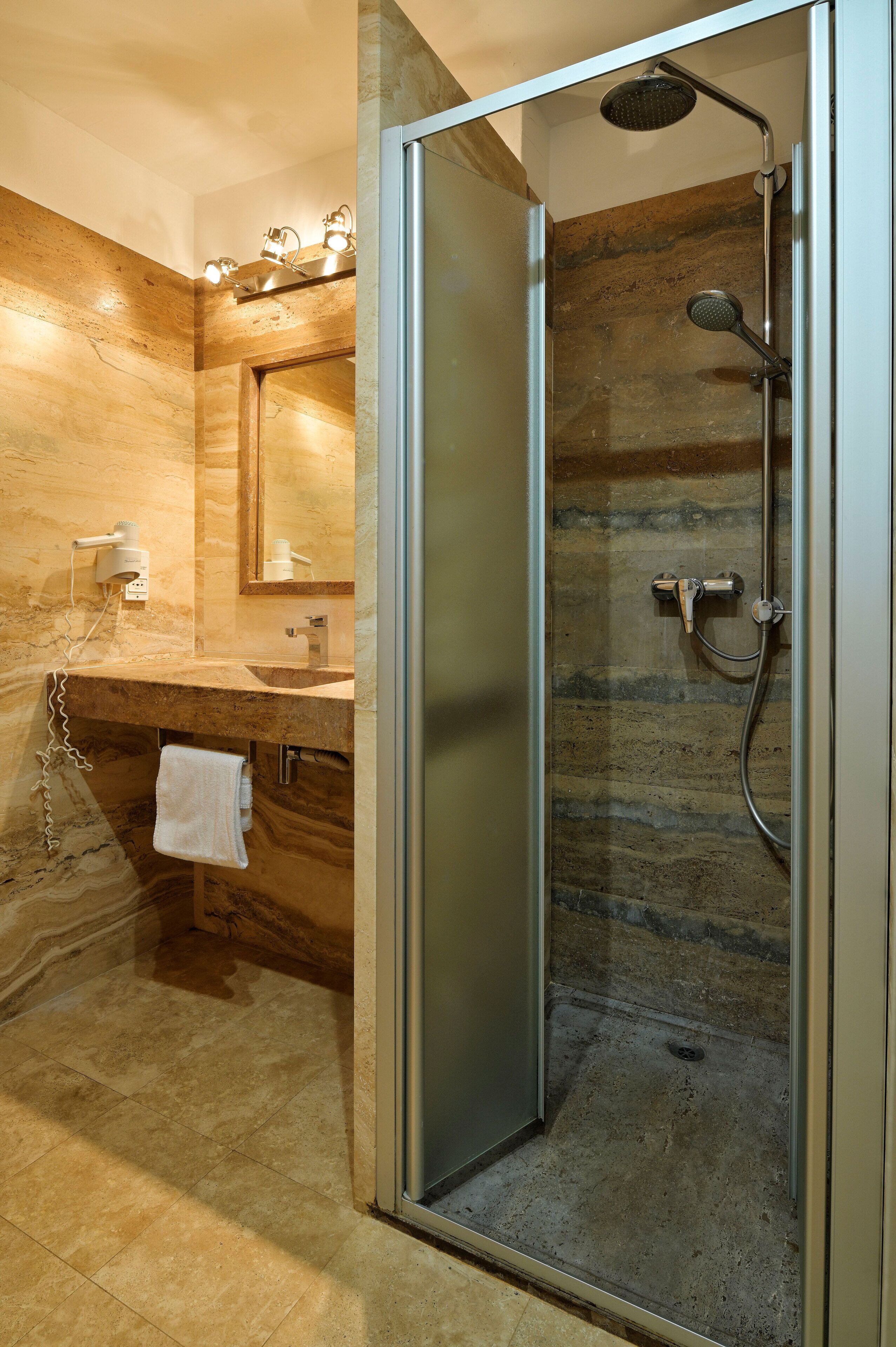 A modern bathroom with a glass-enclosed shower, a vanity with a marble countertop, and a large mirror.