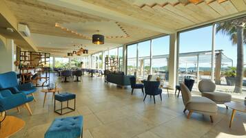 A spacious lobby with modern furniture, large windows, and a wooden ceiling.